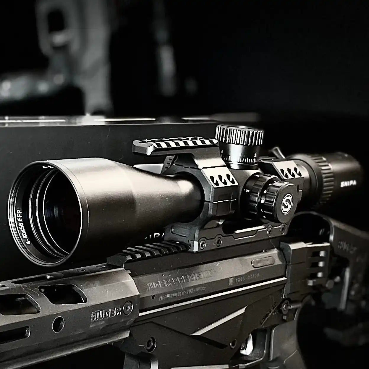 Close-up of SNIPA Yukon Edge 4-40x56 FFP rifle scope with MOA turrets on mounted rifle, black background. TUTT
