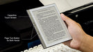 Hand holding e-reader with capacitive touch screen and page turn buttons beside keyboard background TUTT