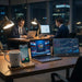 Two individuals working late at night in an office with multiple screens displaying financial data and sports TUTT 15W Wireless Charger – Bamboo Cup Warmer & Phone Standcontent.