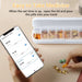 Weekly pill organizer with daily compartments and smartphone showing medication reminders, hand picking pills TUTT
