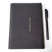 Closed black leather notebook with gold clasp and black pen on white background TUTT
